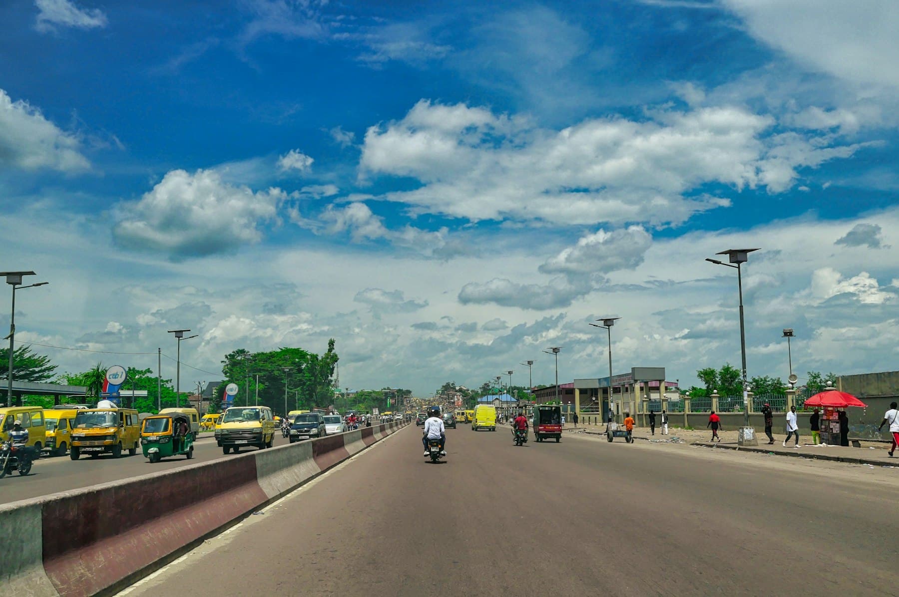 A wide boulevard in Kinshasa under a blue sky